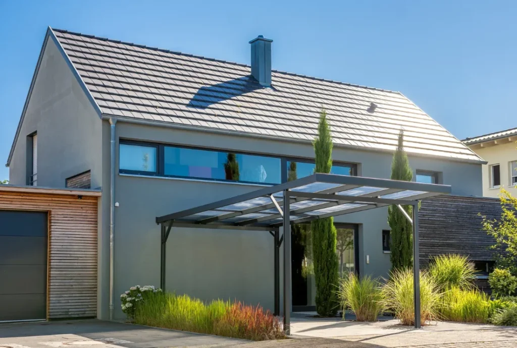 Ein Aluminiumcarport steht vor einem Wohnhaus.