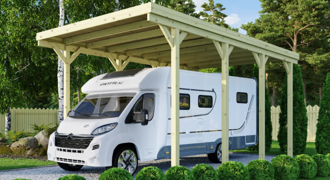 Ein weißes Wohnmobil steht unter einem Holzcarport in Sonderhöhe.