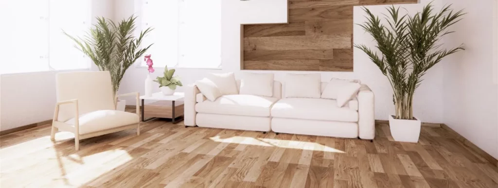 Das Bild zeigt ein helles Wohnzimmer, das eine einladende Atmosphäre ausstrahlt. Im Zentrum des Raumes befindet sich ein weißes Sofa, begleitet von einem passenden Sessel auf der rechten Seite. Links und rechts des Sofas sind zwei große Topfpflanzen zu sehen, die dem Raum ein grünes Element hinzufügen. Auf einem kleinen Tisch neben dem Sofa steht eine Pflanze mit zarten rosa Blüten, die einen Farbtupfer zum Gesamtbild beiträgt. Der Boden besteht aus unterschiedlich gemaserten Holzarten und verleiht dem Raum Struktur sowie Vielfalt. Die Wände schmücken Holzakzente, die für ein warmes Erscheinungsbild sorgen. Große Fenster lassen reichlich Tageslicht hereinströmen und erhellen den gesamten Raum gleichmäßig. Keine Personen sind im Bild sichtbar; Der Fokus liegt ausschließlich auf der harmonischen Einrichtung des Wohnzimmers und den verschiedenen hölzernen Details, die möglicherweise zur Produktpalette von Casando gehören könnten.