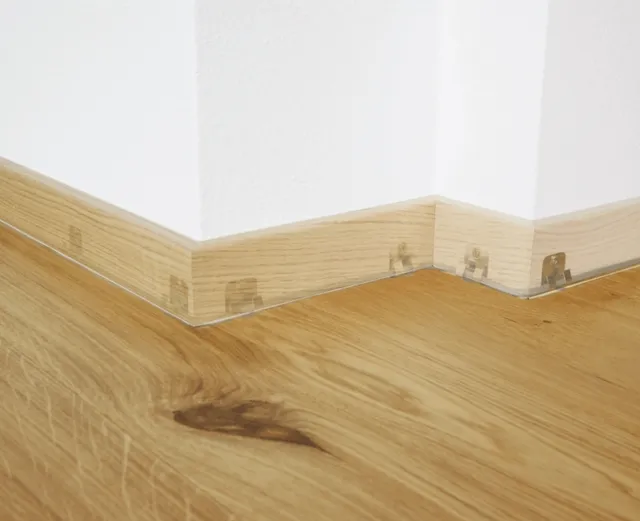 Abgebildet sind helle Holzböden mit passender Fußleiste und sichtbaren Eckbefestigungsklammern.