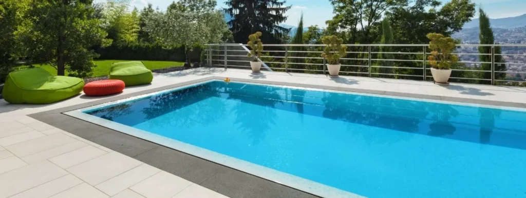 Außenpool in einem Garten mit grünen Sitzsäcken und mehreren Topfpflanzen.
