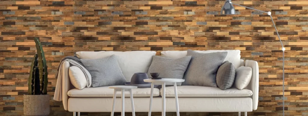 Das Bild zeigt eine ansprechend gestaltete Wohnecke, die den Einsatz von Wandverkleidungen demonstriert. Im Zentrum steht ein weißes Sofa, das mit mehreren grauen Kissen dekoriert ist. Hinter dem Sofa ist eine strukturierte Holzvertäfelung zu sehen, die als stilvolle Kulisse dient. Vor dem Sofa befinden sich zwei kleine, runde weiße Tische. Auf einem der Tische liegt ein grauer Hut, der als dezentes Accessoire Eingang findet. Rechts vom Sofa steht eine elegante Stehlampe mit schlankem Design und links davon schmückt ein Topf mit einer grünen Pflanze den Raum. Die Kombination aus Möbeln und Deko-Elementen schafft eine einladende Atmosphäre in diesem Wohnbereich zum Entspannen oder für gesellige Treffen im eigenen Zuhause oder Gartenhaus.