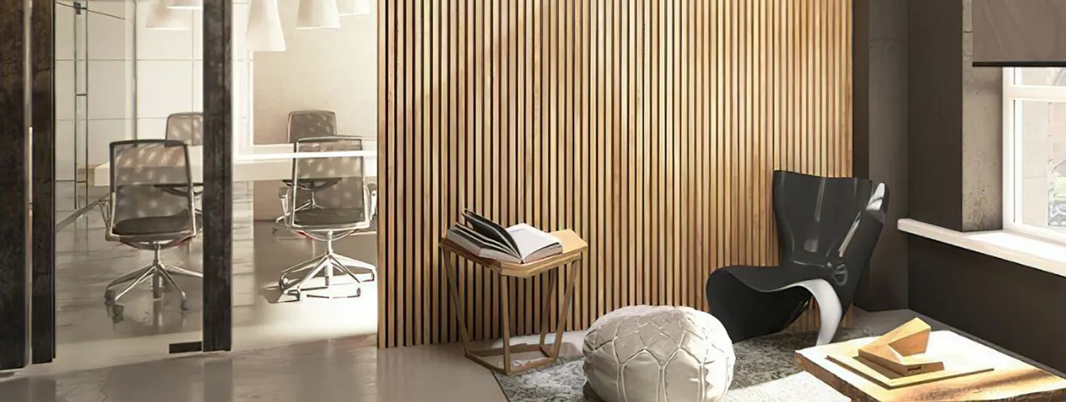 Büro-Loungebereich mit schwarzem Stuhl, Ottomane, Akzentwand aus Holz und neutralem Bodenbelag.
