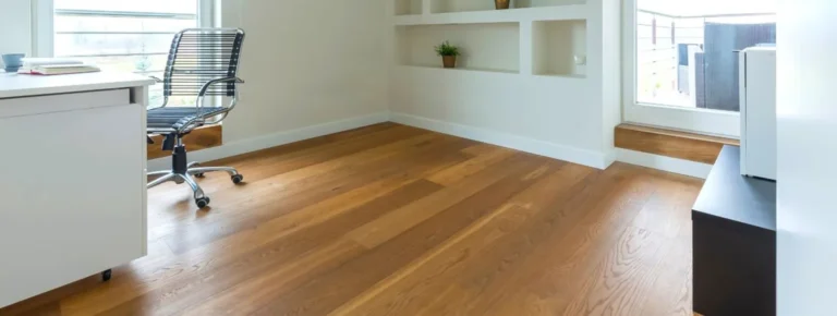 Büroeinrichtung mit Vinylboden, weißem Schreibtisch, schwarzem Stuhl.