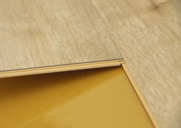 Detailansicht der Verlegung von Vinyl-Bodenbelägen auf gelben Unterböden in einer Küche oder einem Badezimmer.