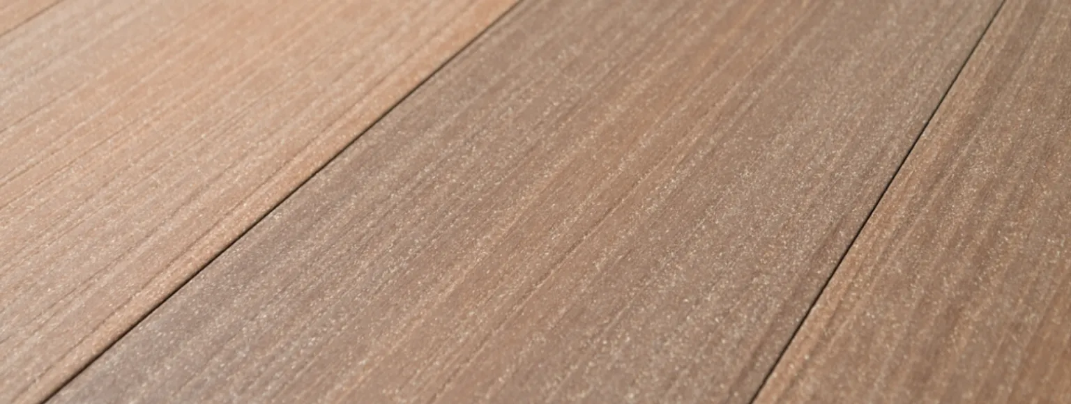 Detailansicht von koextrudierten Terrassendielen mit Holzmaserung und Oberflächenstruktur bei Tageslicht.