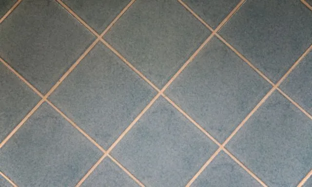 Diagonale Anordnung von blauen quadratischen Bodenfliesen, die ein übliches Laminatverlegemuster zeigen.