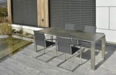 Ein graues Gartenmöbelset aus Metall mit vier Stühlen steht auf einer hellbraunen Holzterrasse.