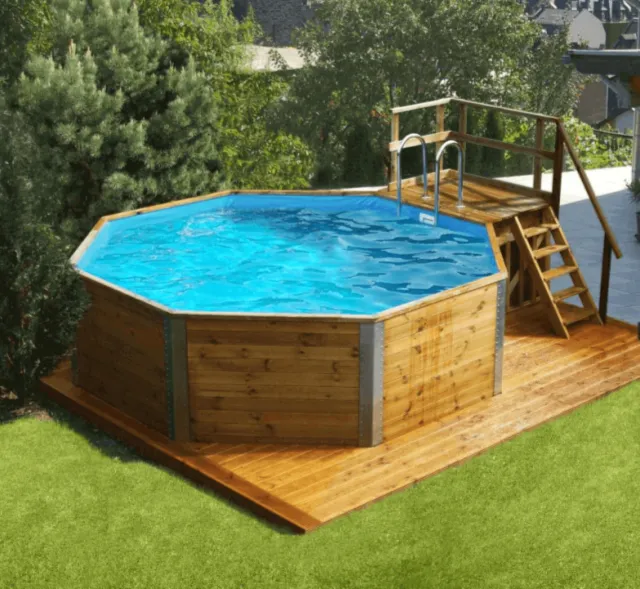 Ein oberirdischer achteckiger Pool mit Holzbelag und einer Metallleiter in einem Garten.