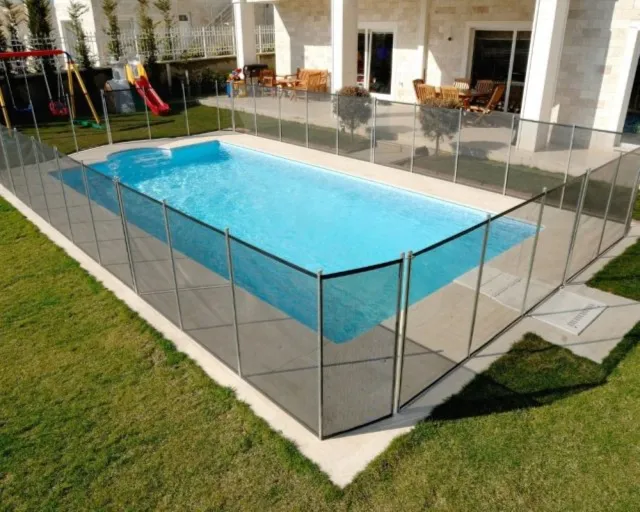 Ein rechteckiger Pool in einem Garten, umgeben von einem Sicherheitszaun und grünem Rasen.
