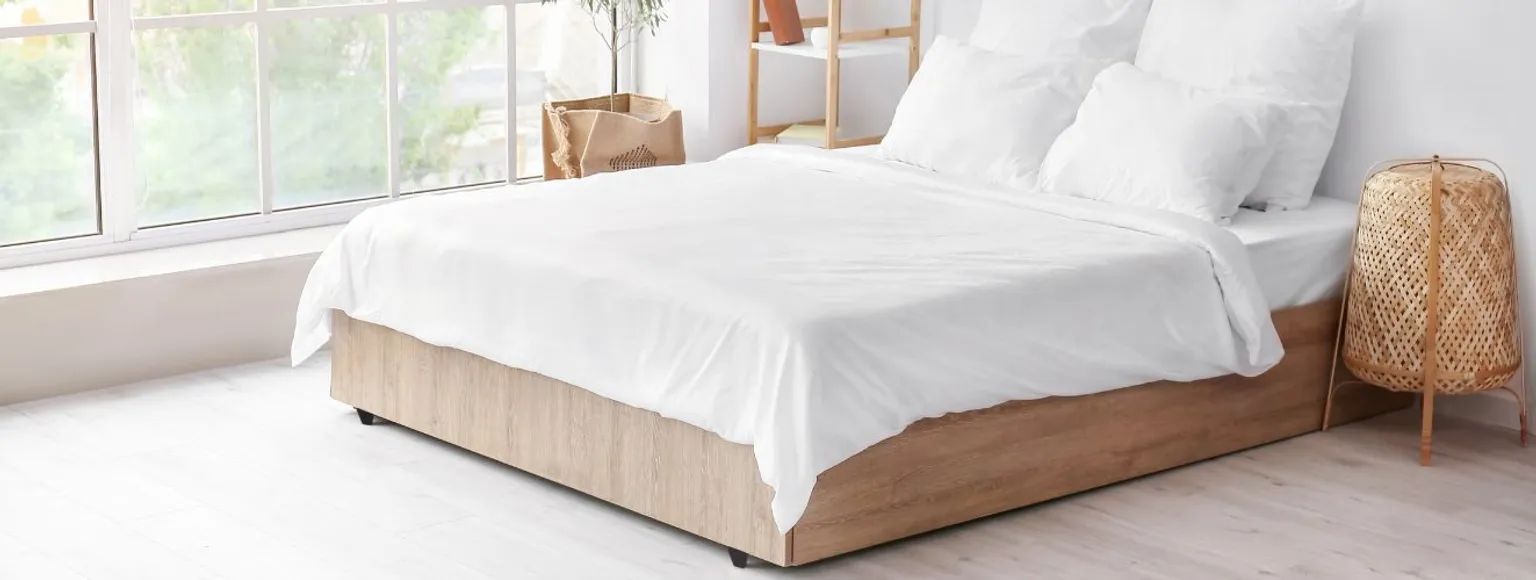 Ein Schlafzimmer mit weißem Bett und hellen Wänden, das mit PVC-freiem Vinylboden ausgestattet ist.