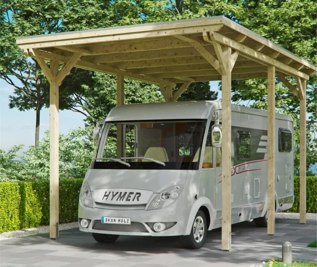 Ein silbernes Wohnmobil ist unter einem hölzernen Carport in einem Gartenbereich mit grüner Umgebung geparkt.