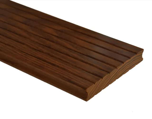 Eine gerillte, dunkelbraune Terrassendiele aus Holz, die schräg auf einer weißen Fläche abgebildet ist.