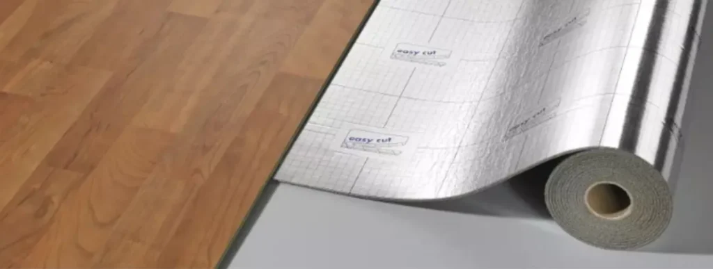 Eine Rolle schalldämmender Unterlage wird unter einem hellen Holzlaminatboden.
