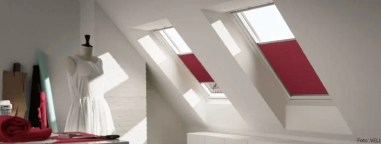 Eine Schaufensterpuppe in einem weißen Kleid steht vor einem Oberlichtfenster.