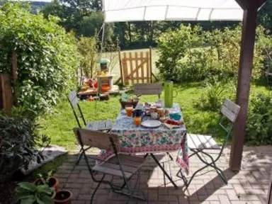 Gartentisch mit Stühlen zum Essen auf einer sonnenbeschienenen, wintertauglichen Terrasse im Hinterhof.