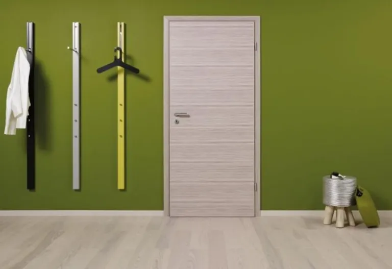 Helle Zimmertür aus Holz neben einer grün gestrichenen Wand in einem modernen Interieur.