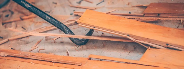 Mit einem metallenen Brecheisen wird der alte Bodenbelag entfernt.