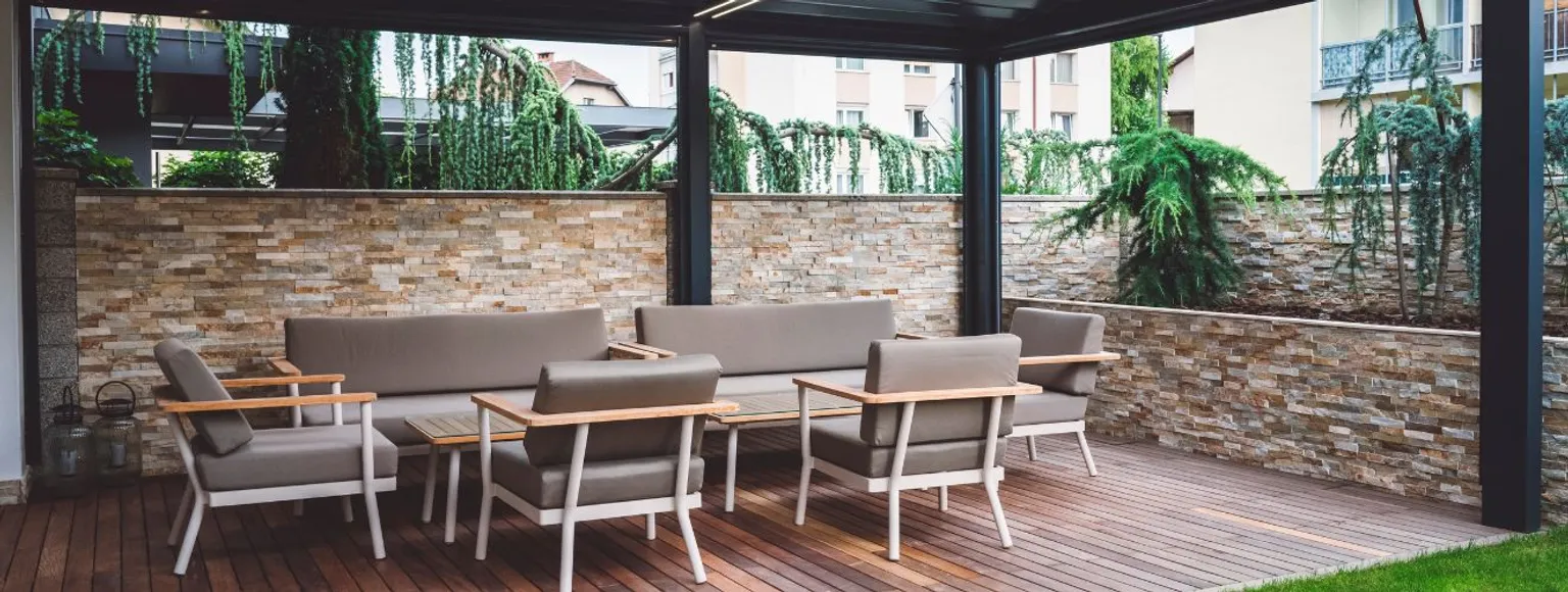 Moderner Außenbereich mit grauen Polstermöbeln und Wandverkleidung auf Terrasse.