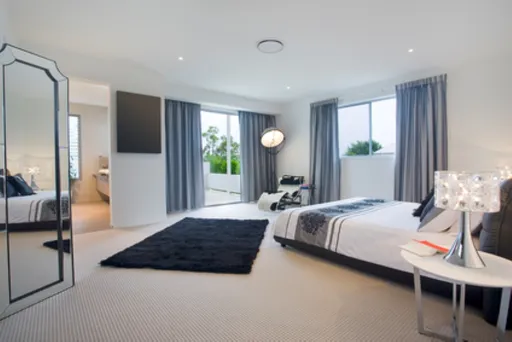 Modernes Schlafzimmer mit grauen Vorhängen, schwarzem Teppich und kreativen Bodengestaltungselementen sichtbar.