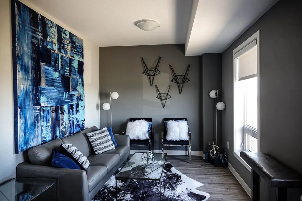 Modernes Wohnzimmer mit abstrakter Kunst, hellen Möbeln und kleiner gemütlicher Sitzecke.