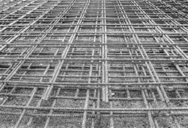 Rechteckiges Stahlgitter, das zur Betonbewehrung eines Gartenfundaments auf den Boden gelegt wird.