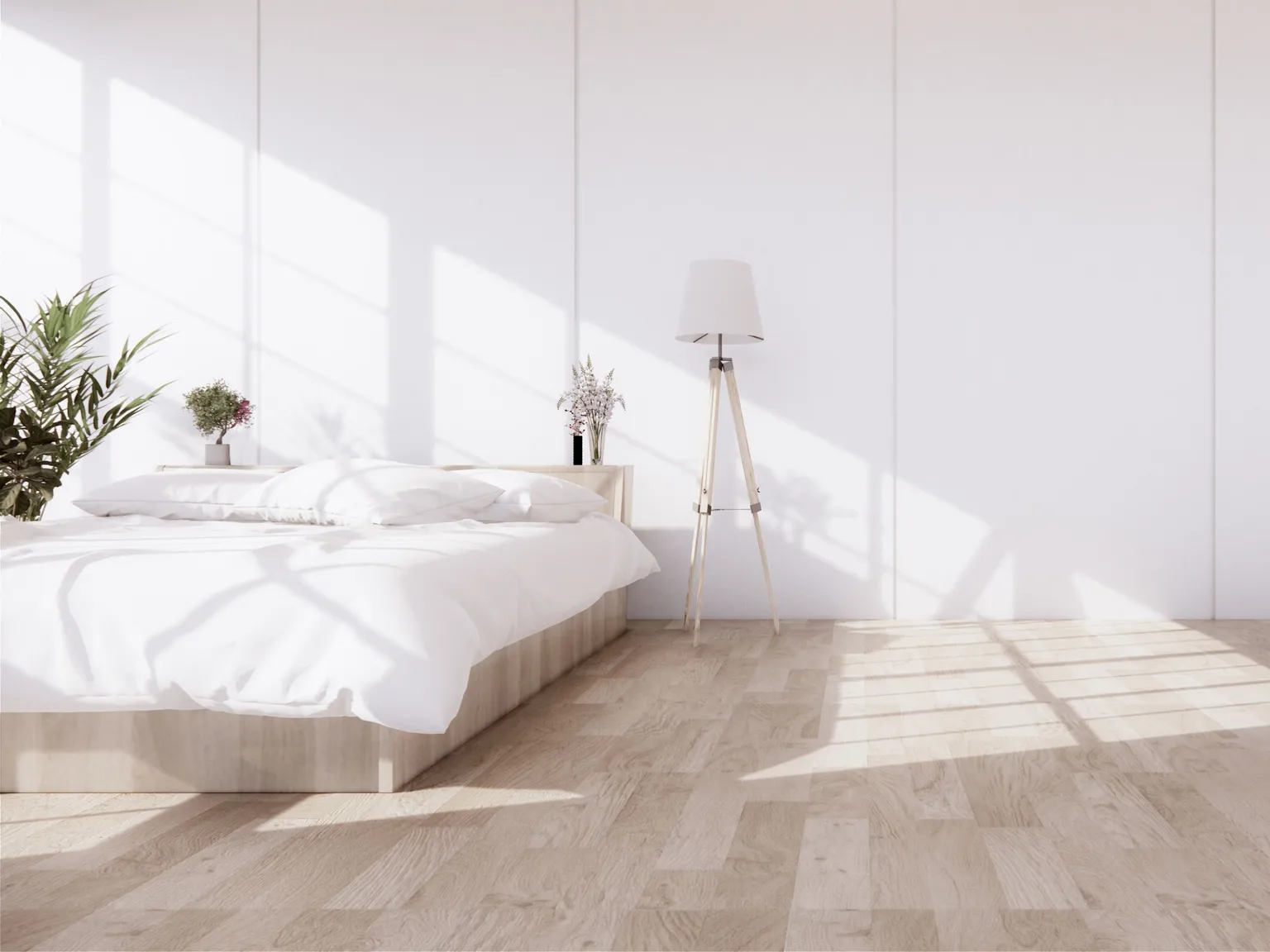 Schlafzimmer mit weißem Bettzeug, Zimmerpflanzen, Stehlampe und hellem Parkettfußboden.
