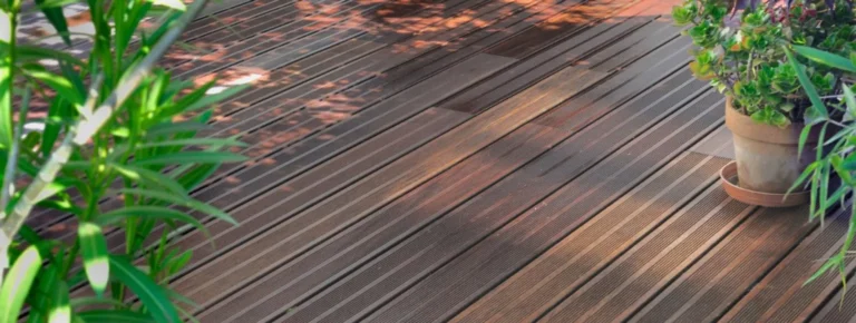 Thermoholz-Terrasse mit sichtbarem Sonnenlicht Schatten und mehreren grünen.