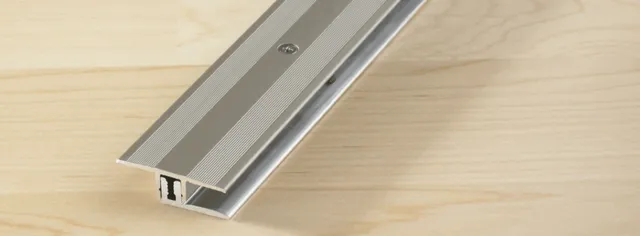 Türschwellenleiste aus Metall auf hellem Hartvinylboden-Parkett.