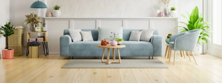 Wohnzimmer mit blauem Sofa, Holzfußboden Grünpflanzen und einem Couchtisch.