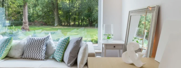 Wohnzimmer mit gemusterten Kissen weißen großen PVC-Fenstern und Blick.