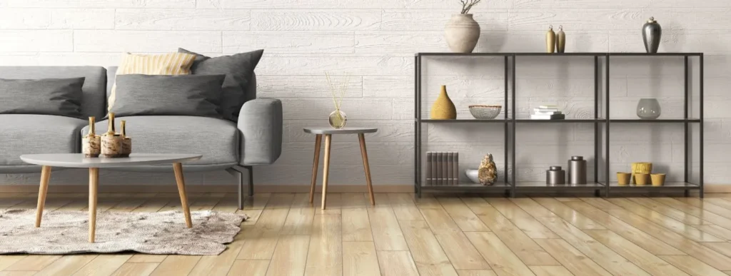 Wohnzimmer mit grauem Sofa, Holztischen und Regalen aus hellem Holzlaminat