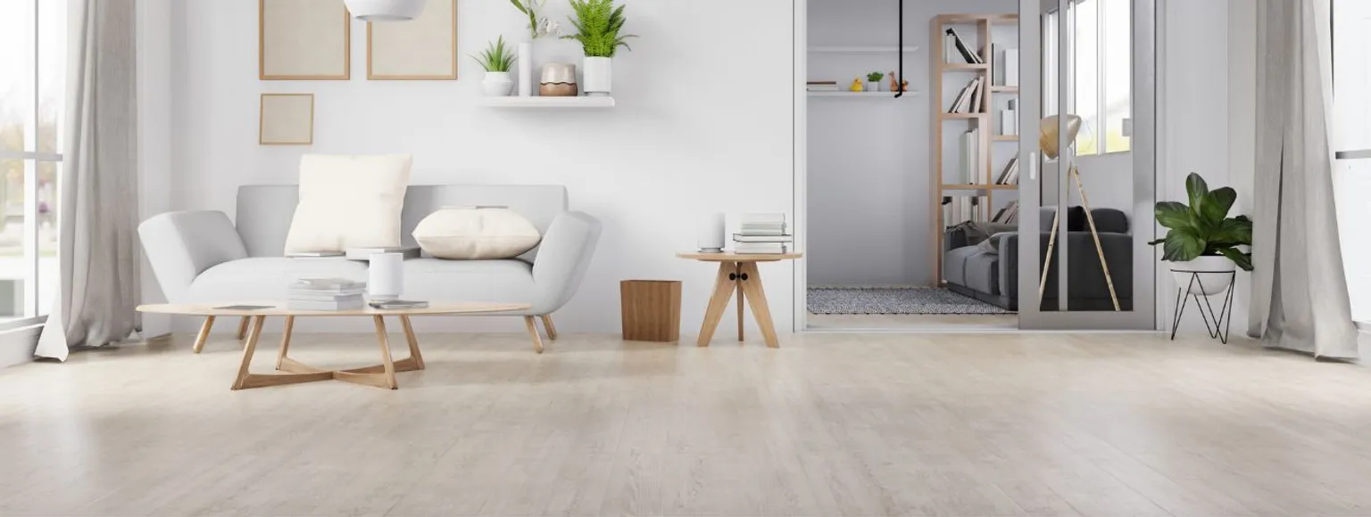 Wohnzimmer mit Korkfußboden, weißen Wänden, Sofa, kleinem Tisch und einfacher Dekoration.