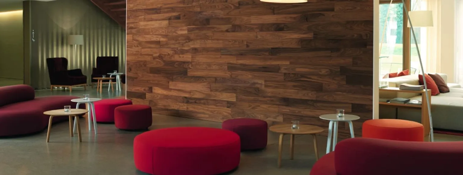 Zeitgenössische Lounge-Einrichtung mit roten Stühlen, runden Tischen und Wandpaneelen wird installiert.