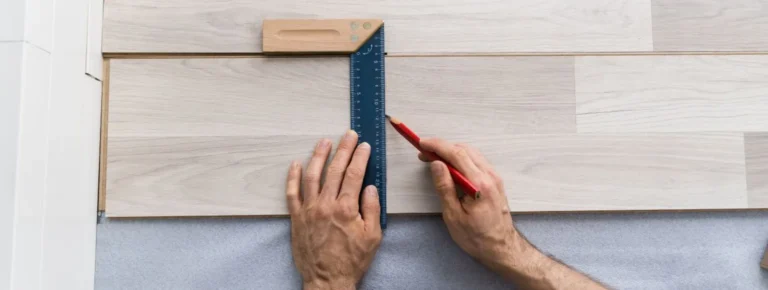 Hände messen Laminatboden mit Lineal während der Verlegung