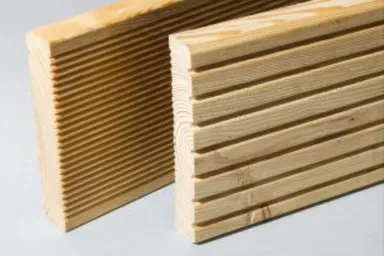 Zwei Terrassendielen aus Nadelholz stehen mit gleichmäßigen Rillen nebeneinander.