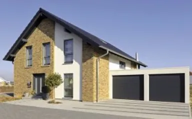 Zweistöckiges Haus mit roter Backsteinfassade, Doppelgaragentoren, gepflasterter Einfahrt und blauem Himmel.
