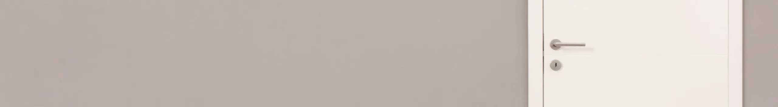 Beigefarbene Wand mit weißer Innentür mit silbernem Griff auf der rechten Seite.