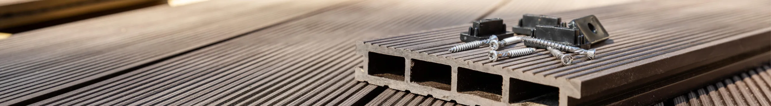 Nahaufnahme von braunen Terrassendielen aus Verbundwerkstoff mit sichtbaren Schrauben und Clips.