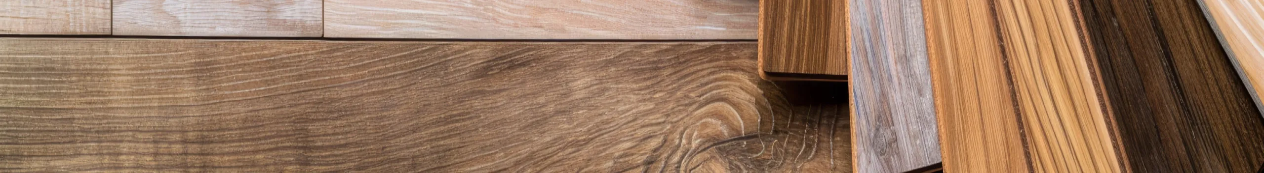 Verschiedene Laminat- und Holzfußbodenmuster nebeneinander auf einer neutralen Fläche angeordnet.