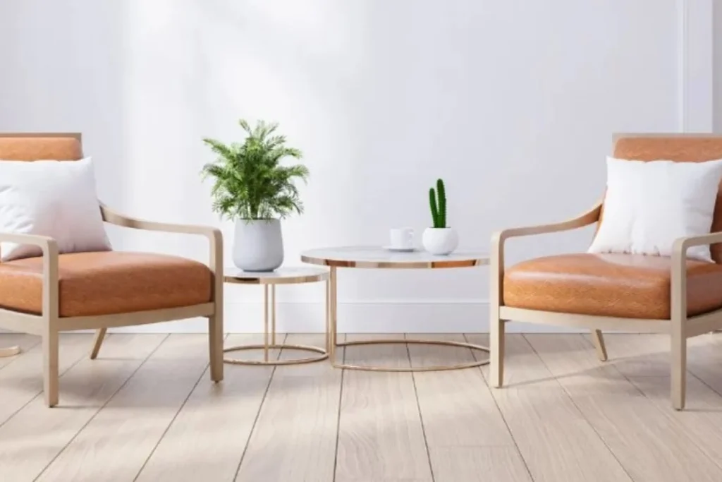 Zwei Sessel mit weißen Kissen, kleine Tische, Accessoires und Grünpflanzen auf dem Boden.