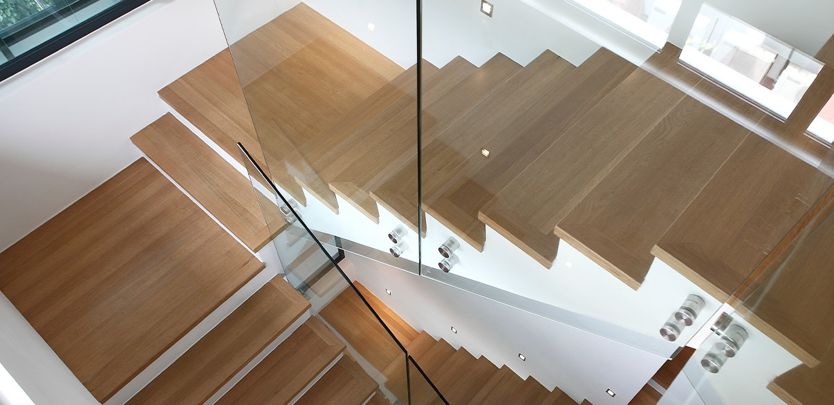 Treppe mit Glasgeländer und vinylverkleideten Stufen in einem neutralen.