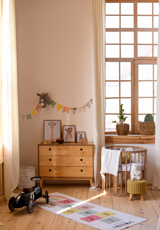 Natürlich eingerichtetes Babyzimmer mit großem Fenster, Holzmöbeln und hellem Dielenboden – das Bild ist klickbar und führt direkt zum passenden Holzboden im casando-Shop
