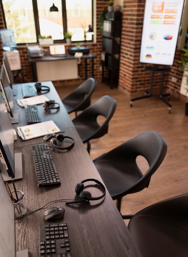 Büro mit Arbeitsplätzen, Computern, Headsets und modernem, hellem Bürofußboden.