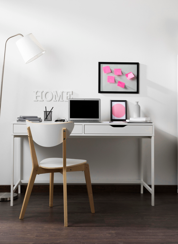 Heimbüro mit hellem Schreibtisch, Stuhl, Lampe, Laptop und modernem Bodenbelag in Holzoptik.