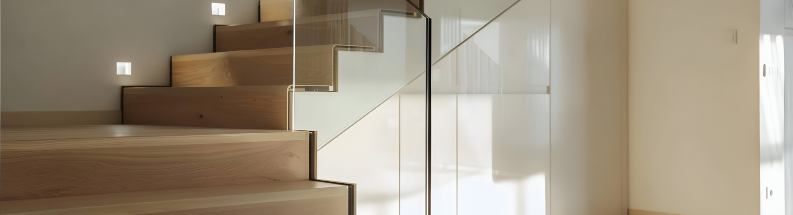 Holztreppe mit Glasgeländer und vinylbeschichteten Stufen, beleuchtete Wandlampen.