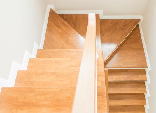 Eine gewendelte Treppe mit warmem Laminat in durchgehender Holzoptik. Die Tritt- und Setzstufen sind passgenau verkleidet, die Fugen sauber verarbeitet – ein Beispiel für gelungene Renovierung mit Laminat. Bild ist klick bar und führt zum passendem Laminat