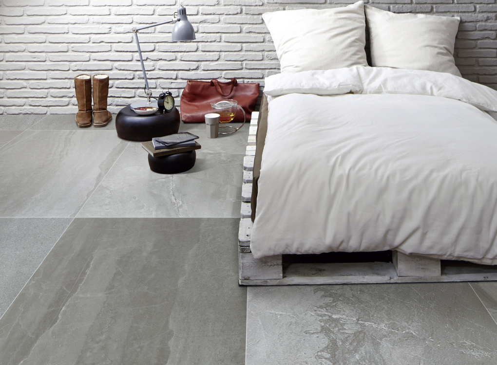 Modernes Schlafzimmer mit großformatigen, grauen Bodenfliesen in Betonoptik – kühl, minimalistisch und besonders pflegeleicht. Ideal für puristische Einrichtungsstile oder als Grundlage für Kontraste mit Textilien. Das Bild ist klickbar und führt zum passenden Produkt im casando-Shop.