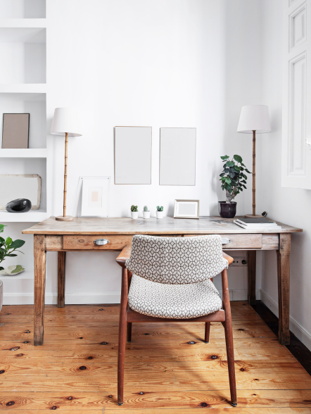 Home-Office mit Holzschreibtisch, gemustertem Stuhl und hellem Holzfußboden in hellem Raum.