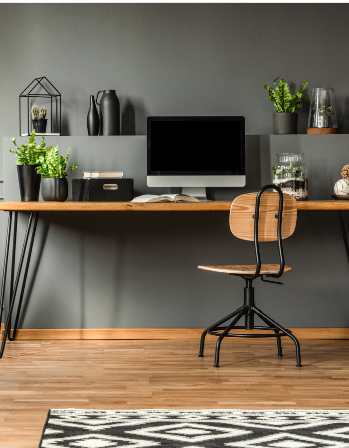 Modernes Heimbüro mit Holzfußboden, Grünpflanzen, Schreibtisch, Computer und Stuhl sichtbar.